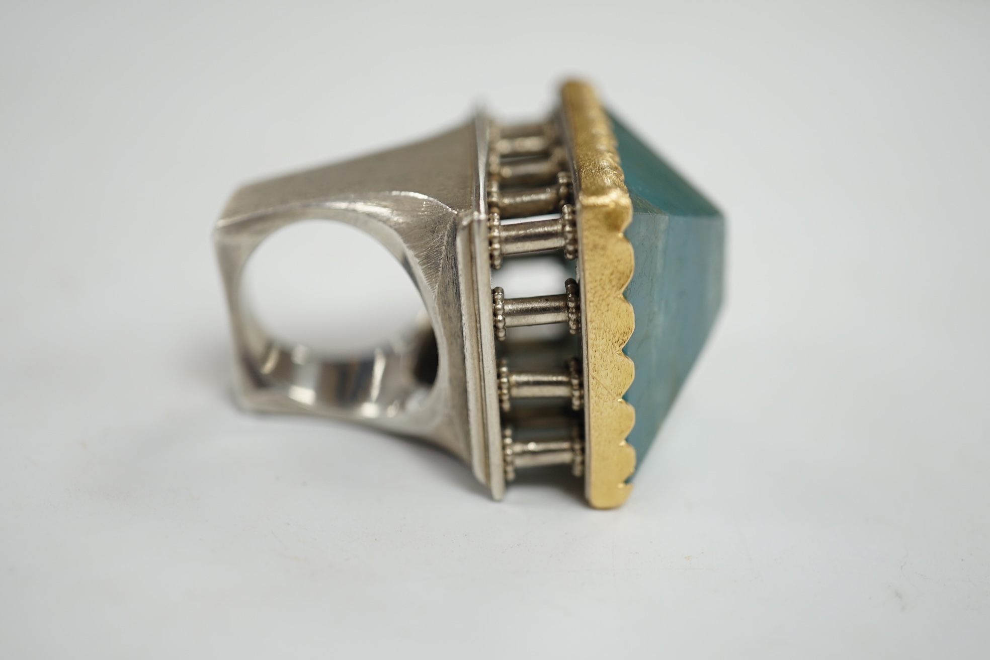 An unusual recent German 925, yellow metal and shaped cut aquamarine set architectural dress ring, the stone weighing approximately 79.00ct, size O/P, gross weight 67 grams. Condition - fair to good